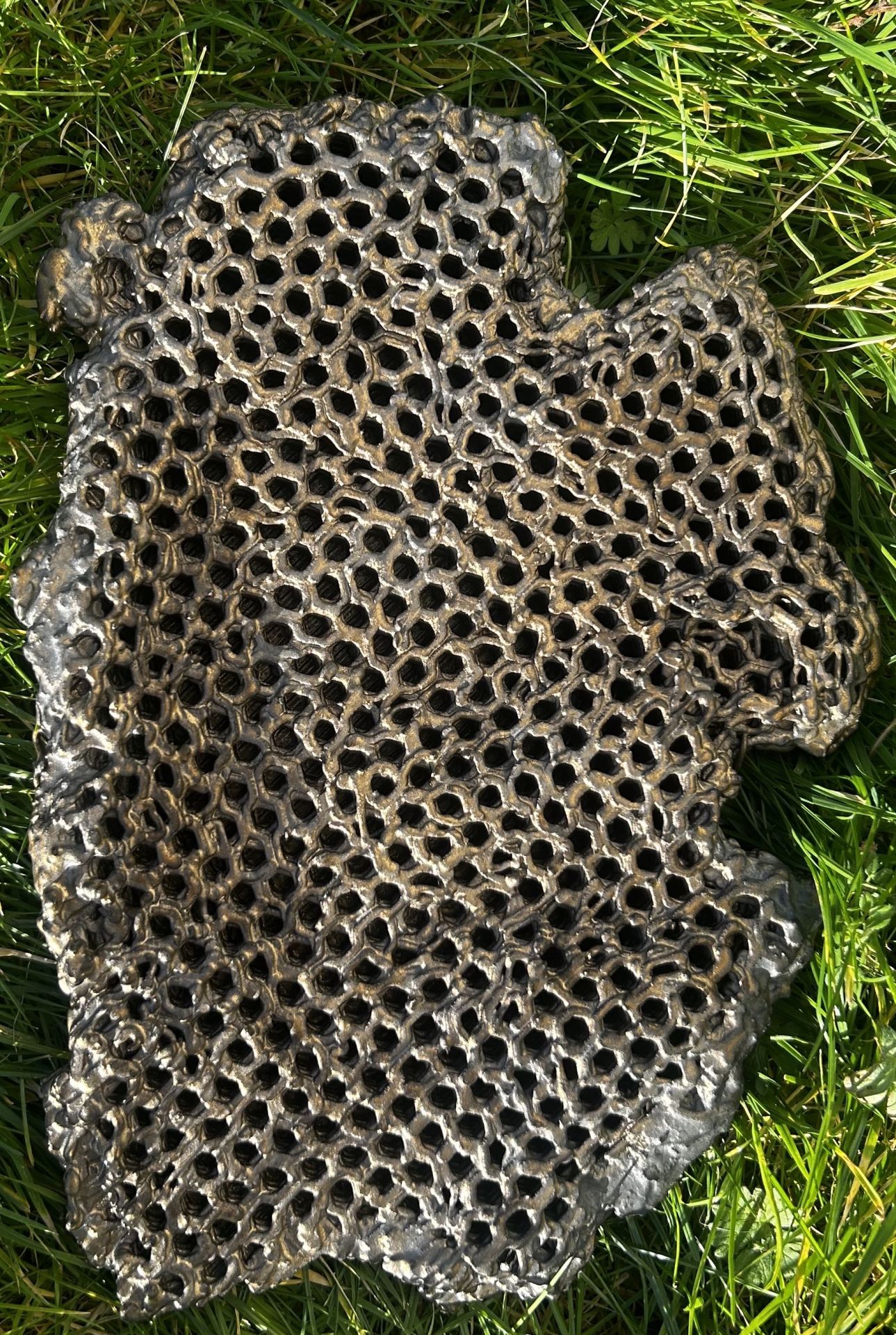 A 3-d printed ceramic honeycomb with reflective bronze glaze.
