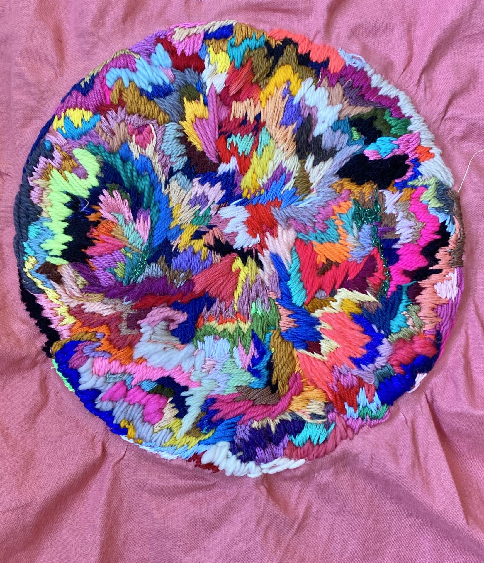 An image of a circle embroidered using many colours.