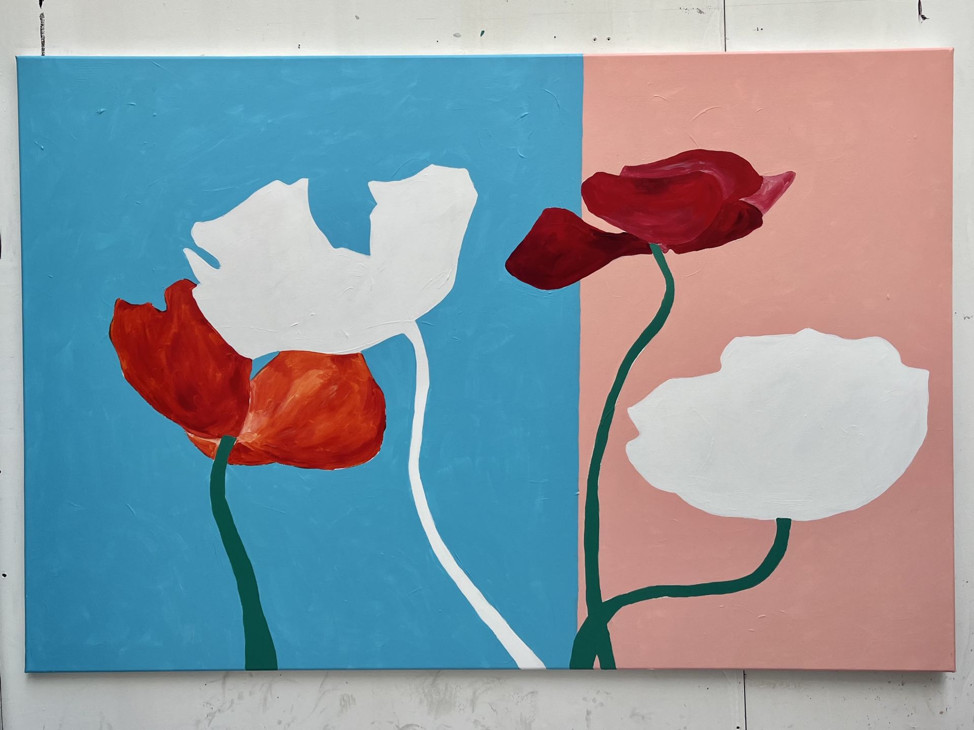 A painting of red and white flowers, against a white wall.