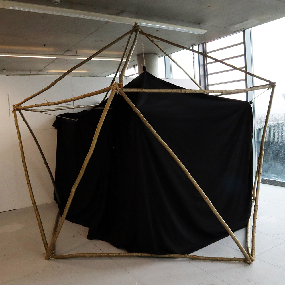 An image of a black, tent-like structure held up with several poles.