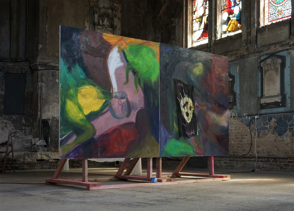Large painting suspended on a timber frame in a chapel with stained glass windows behind.