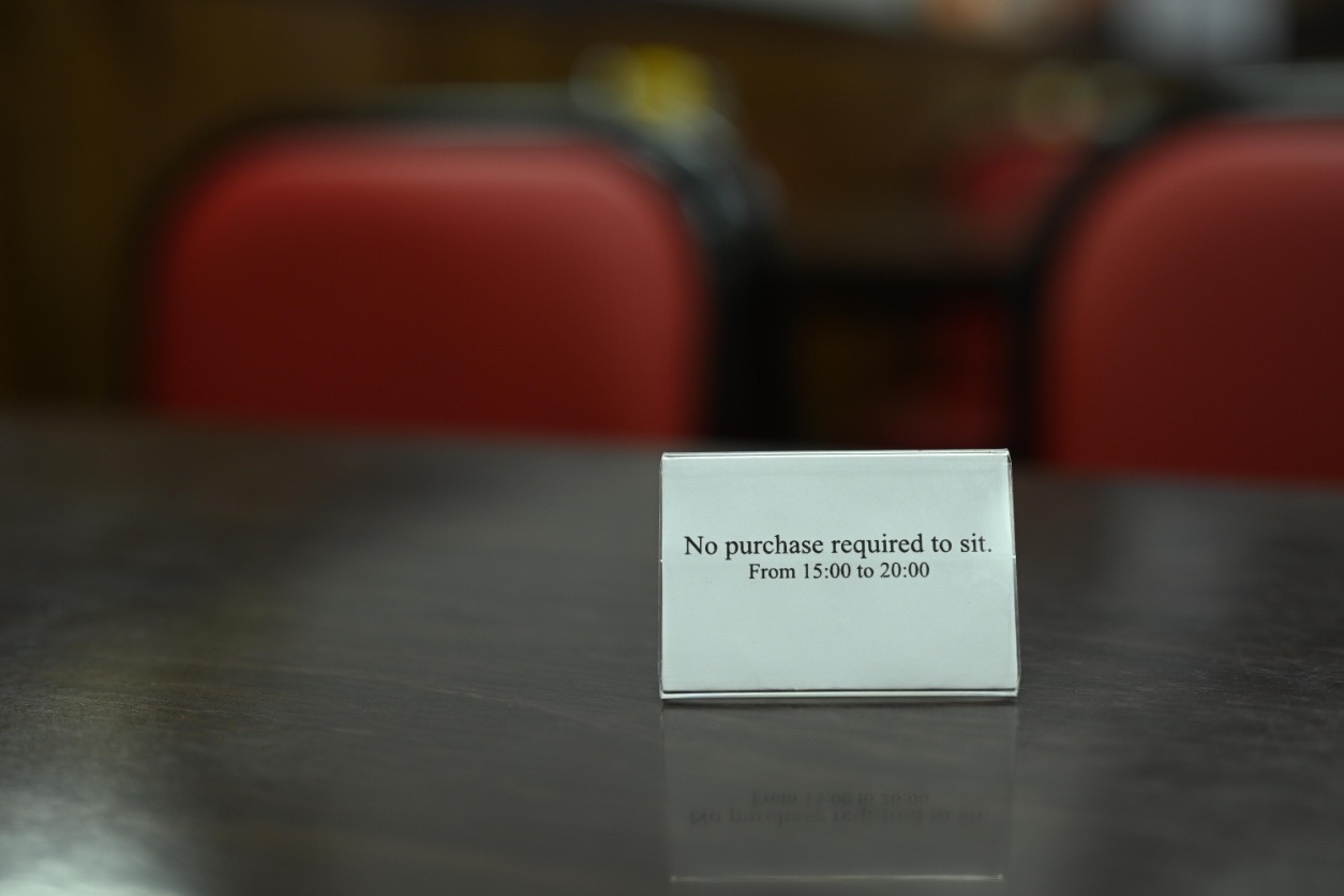 An image of an acrylic name card holder with the line "No purchase required to sit. From 15:00 to 20:00" printed on a white background.