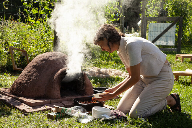 Documentation of a community-based project with cob oven, clay, beans, pots, and dried plants.