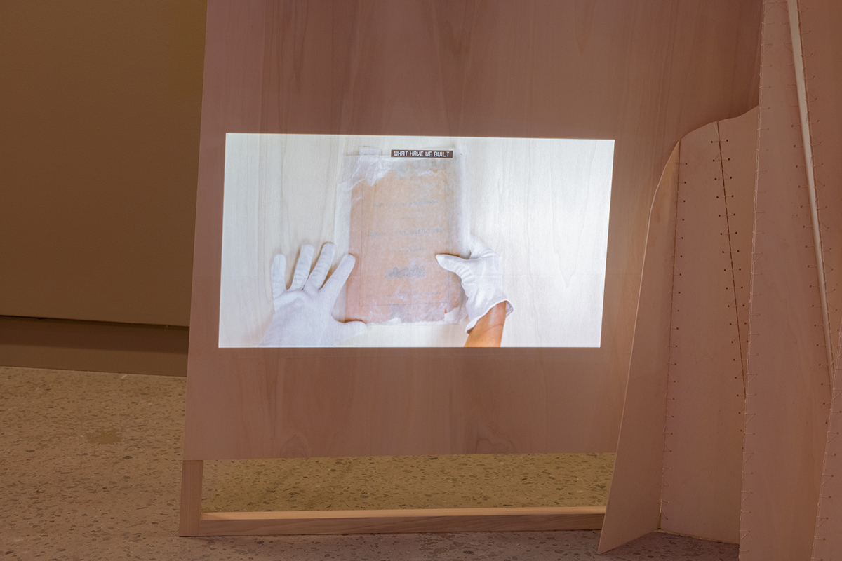 Exhibition views of an exhibition featuring big wooden structures on which video works are projected