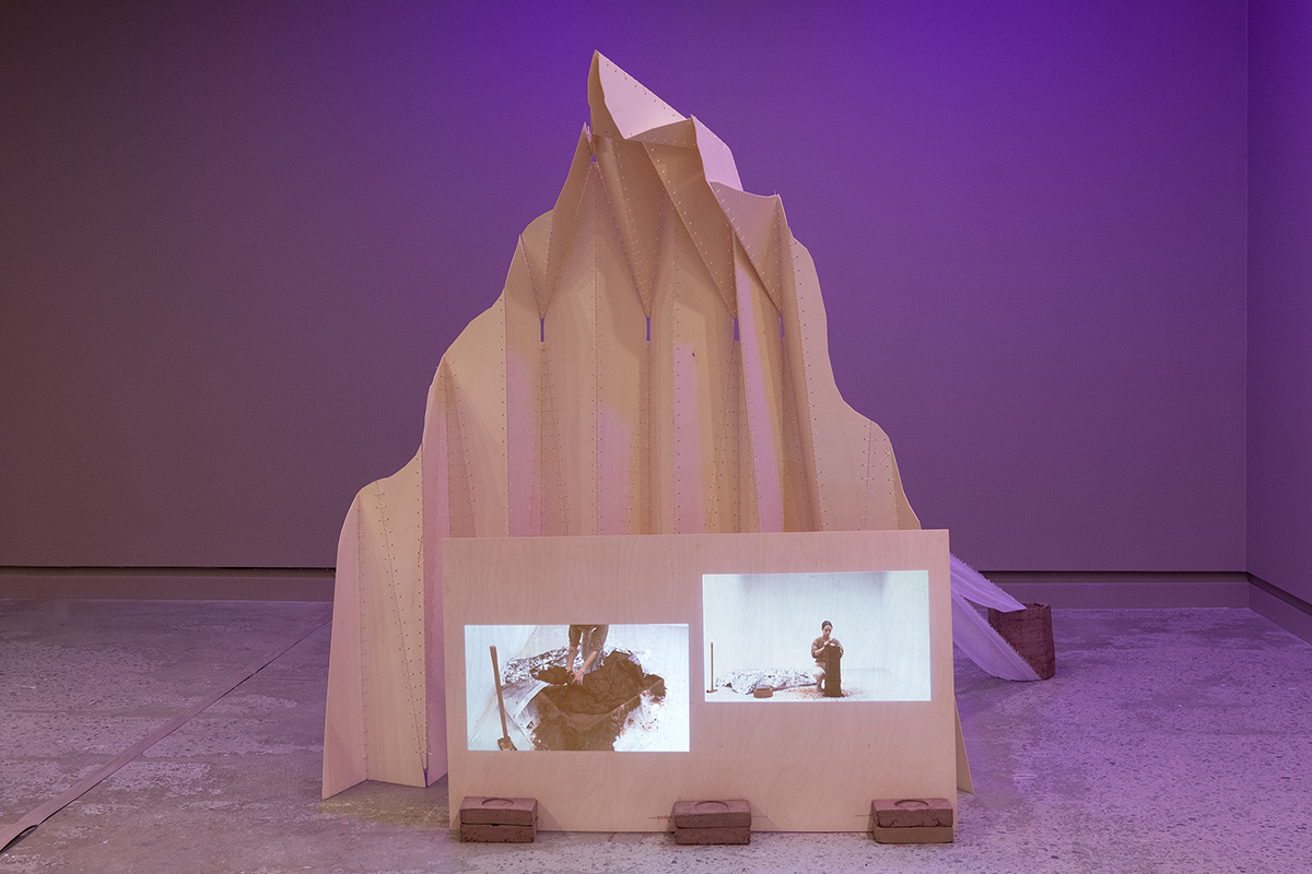 Exhibition views of an exhibition featuring big wooden structures on which video works are projected