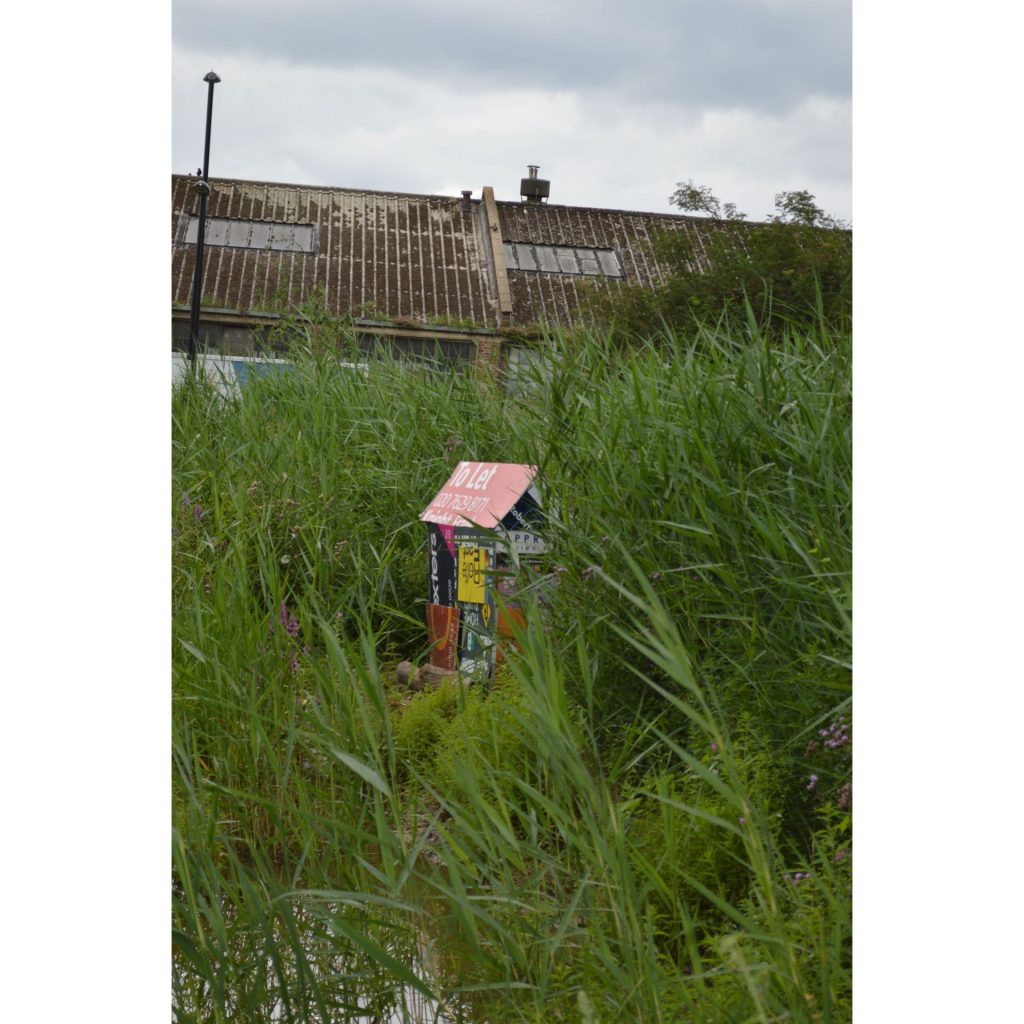 Photography of an installation at Folkstone Gardens of a house made out of Let by/For sale advertisement boards
