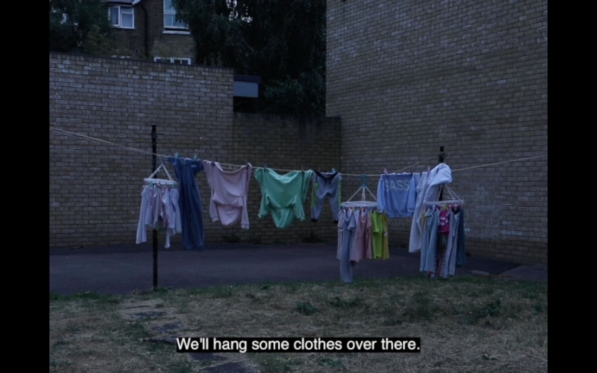 A video still of several brightly coloured clothes on a washing line at dusk.