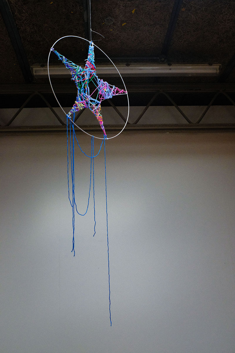 A suspended sculpture of a colourful star shape on a hoop.