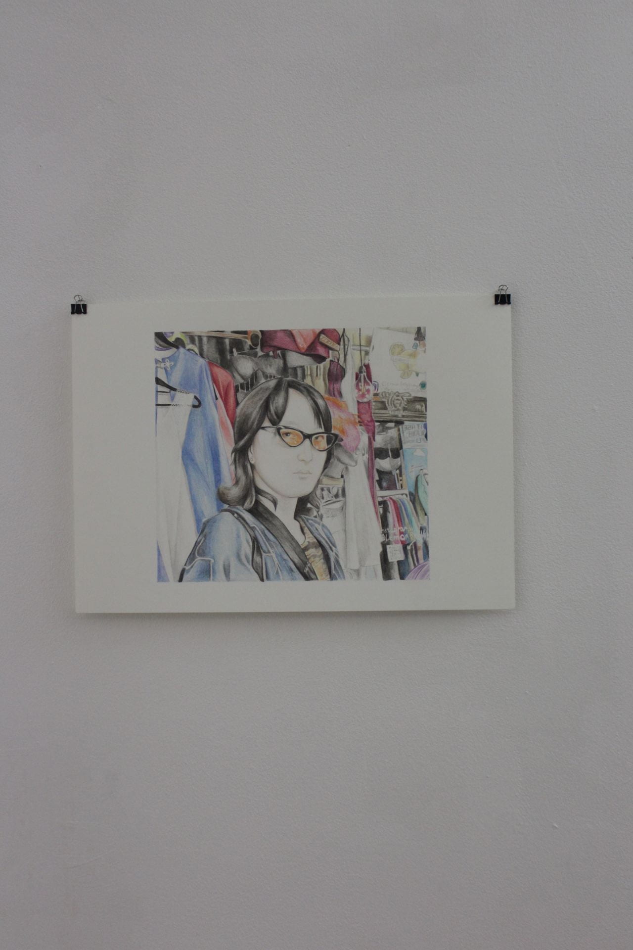 An image of a coloured pencil drawing of a person on a white wall.