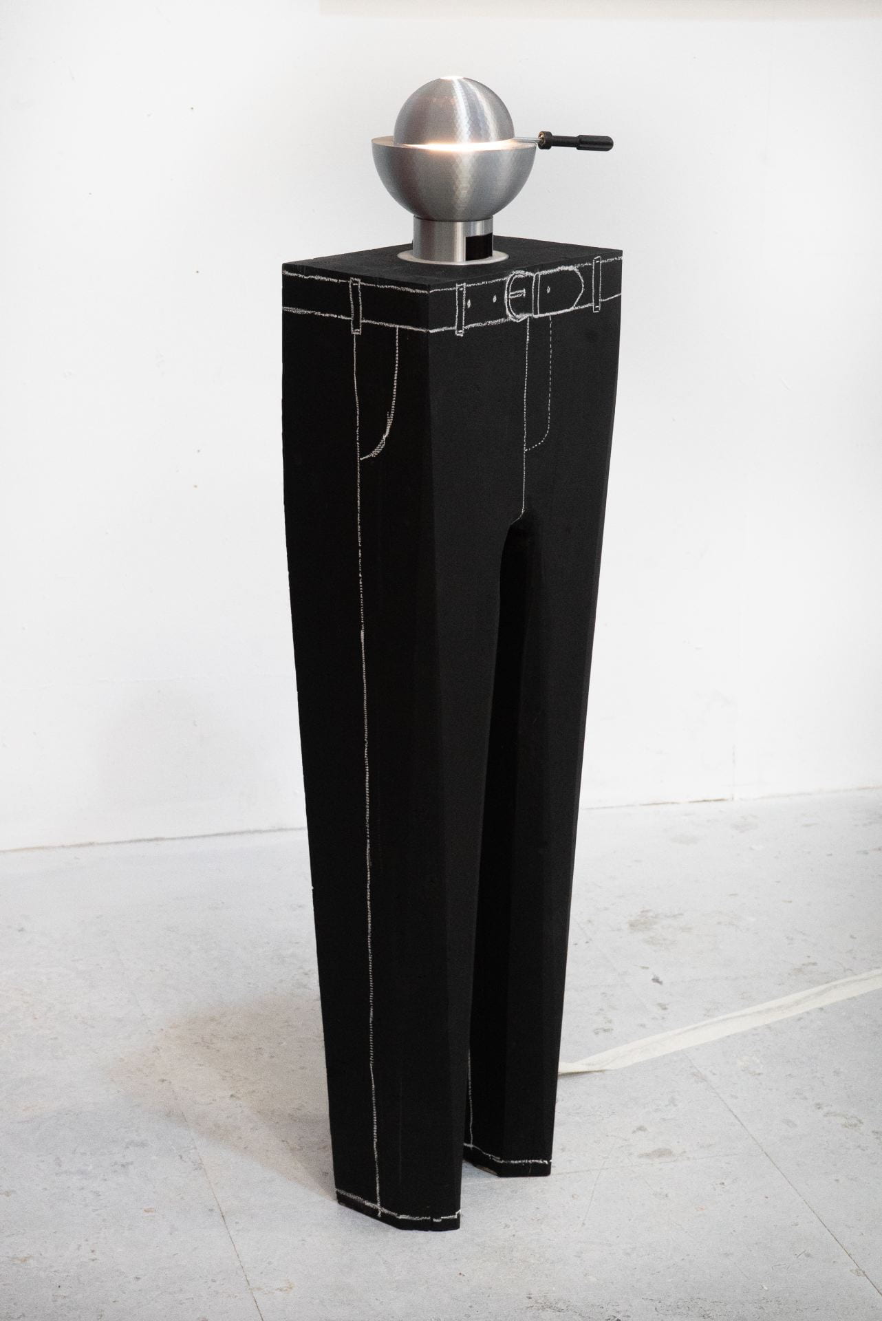An image of a stiff pair of black trousers with chalk details and a 3D printed lamp on top.