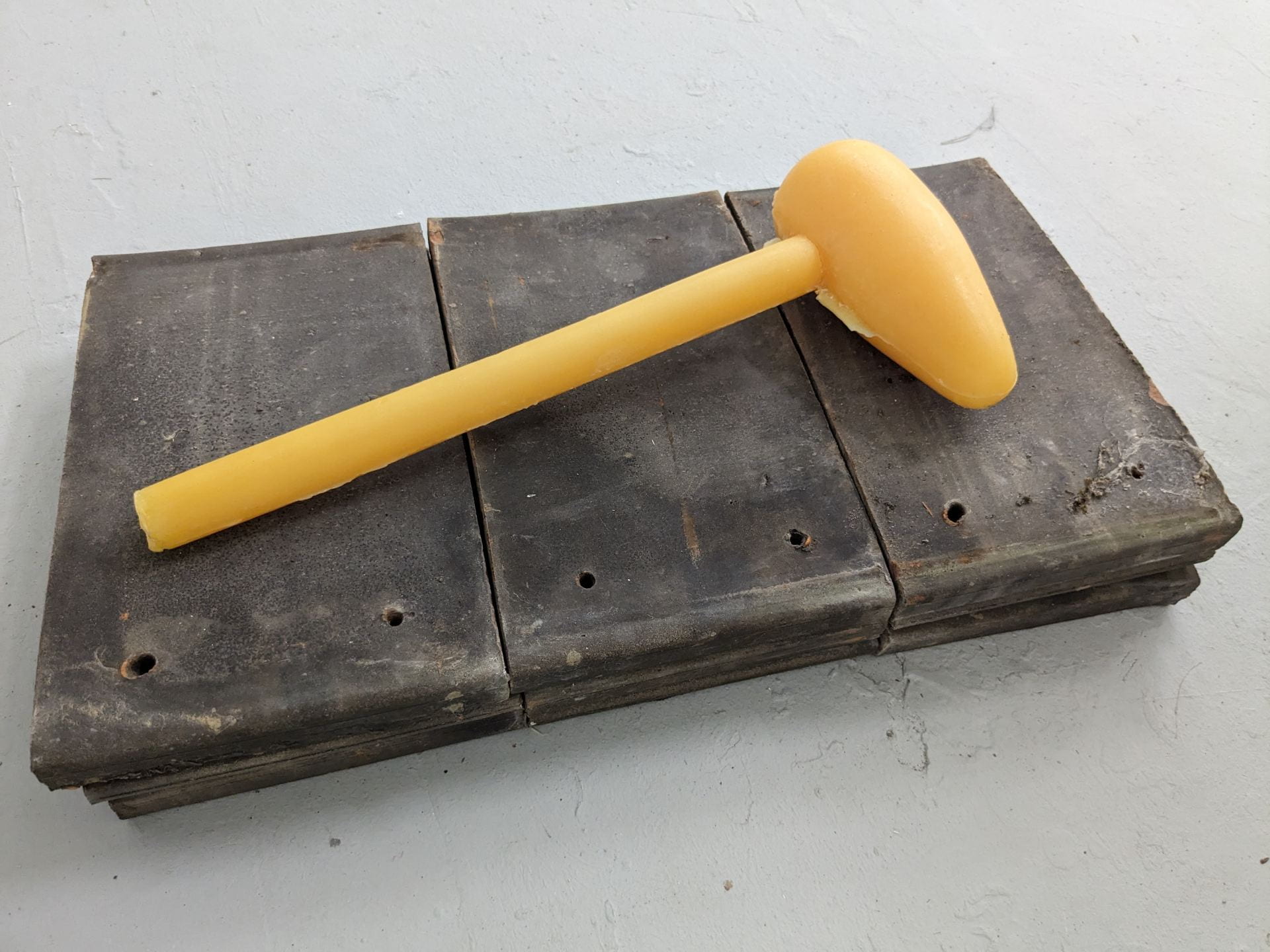 An image of a wax mallet sat on some wooden flooring.