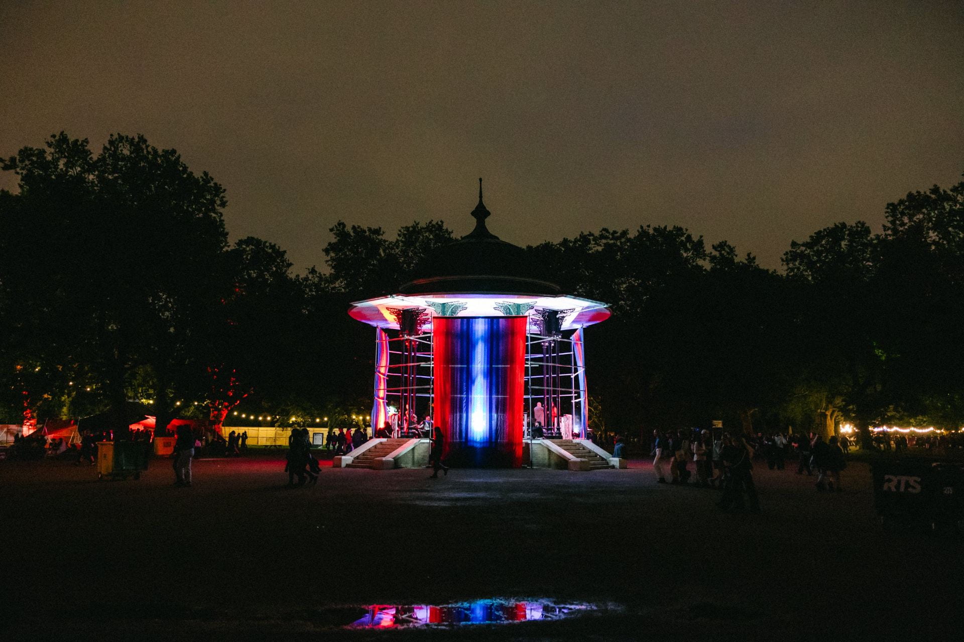 A bandstand draped in red and blue fabric is lit by spotlights during the evening at Rally festival.