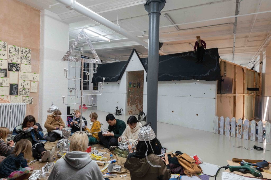 A group of adults and children working together to make a tinfoil sculpture as part of the public programme for this group show. 