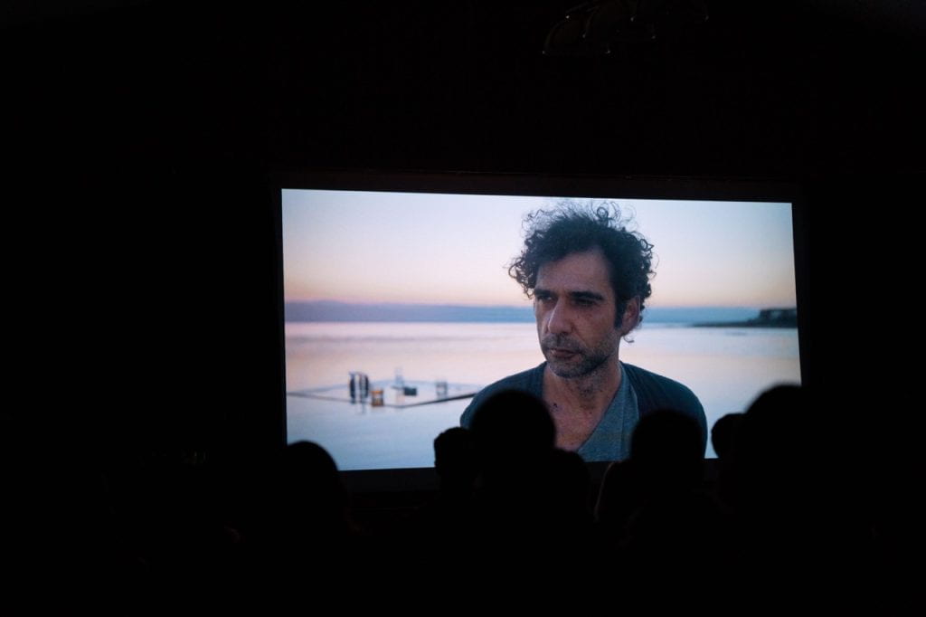 A picture of SET Film festival, showing a still from a film showing a man looking out at a lake.