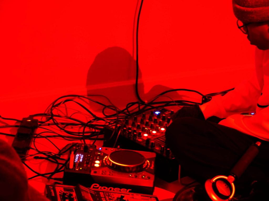A person performing a sonic performance in a red room.