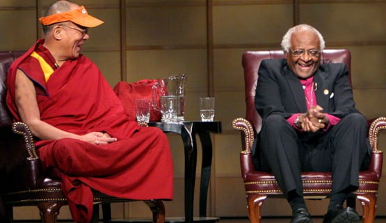 Colour photograph landscape of The 14th Dalai Lama and Archbishop Desmond Tutu, both Nobel Peace Prize laureates, in Vancouver, British Columbia, in 2004. Both seated and laughing at the same time.