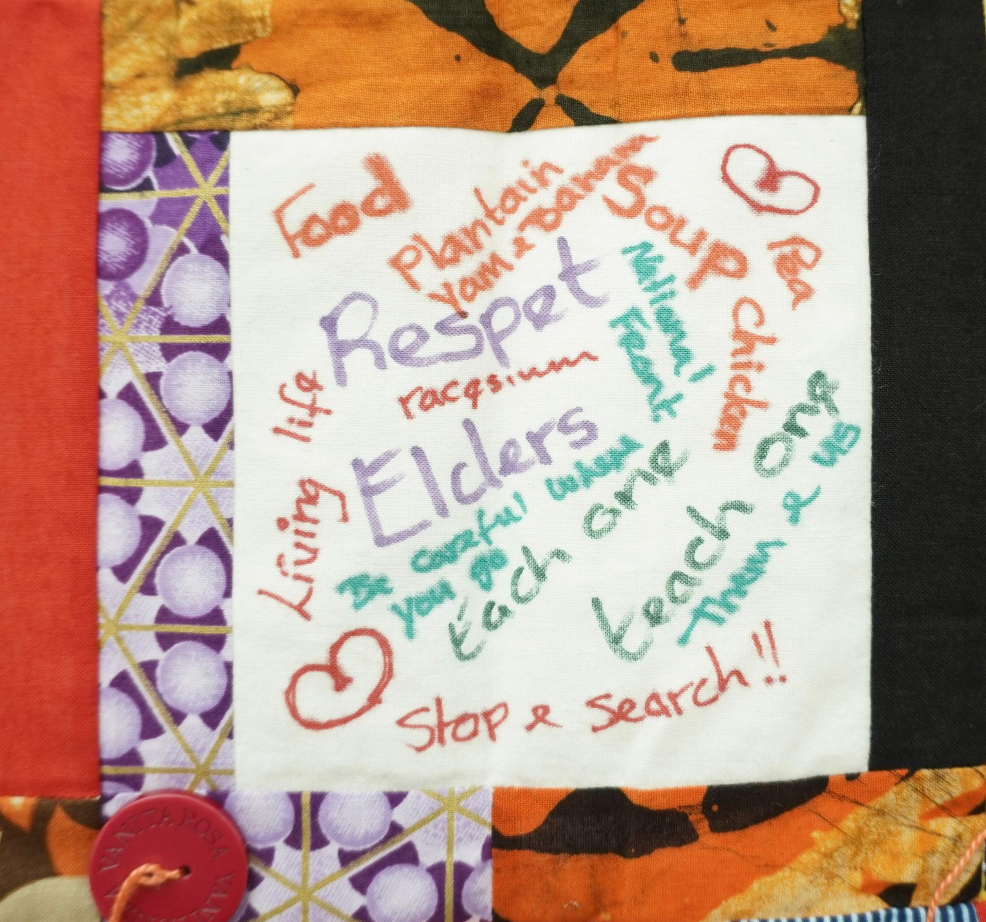 Commemorative quilt. Text reads, 'Food, plantain, respect, elders, stop and search, each one teach one, living life, yam and banana, national front, racism'