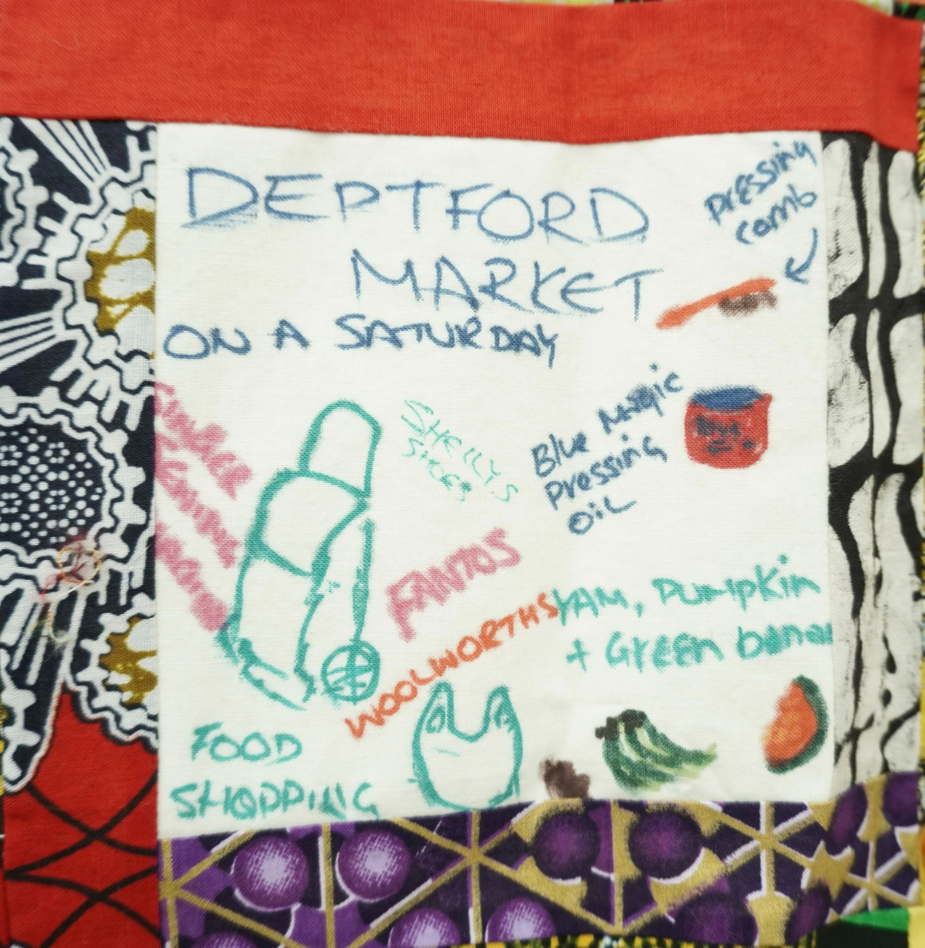 Commemorative quilt. Text reads, 'Deptford Market on a Saturday, blue magic pressing oil, yam, pumpkin and green banana, food shopping, Woolworths, Fantos, Singer sewing machine'