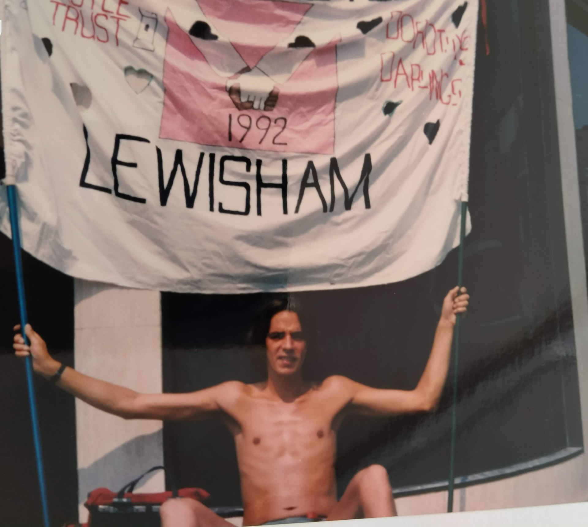 A shirtless man holding a banner in the sunshine