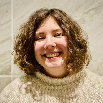A portrait of Niamh, who is smiling wearing a beige jumper