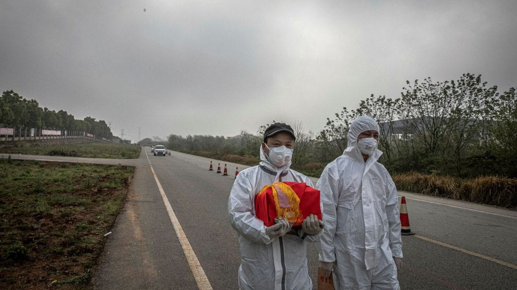 Wuhan: A resident wearing protective gear carries the remains of a deceased loved one.
