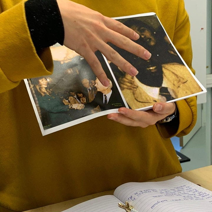 A person holds a magazine and points at the double page with their right hand