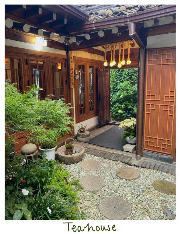 Inside of a Japanese teahouse with brown wooden doors, pebble floor and plants
