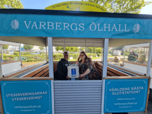 Two women smiling at the camera from the inside of a blue carriage intended to explore the Varbergs area.