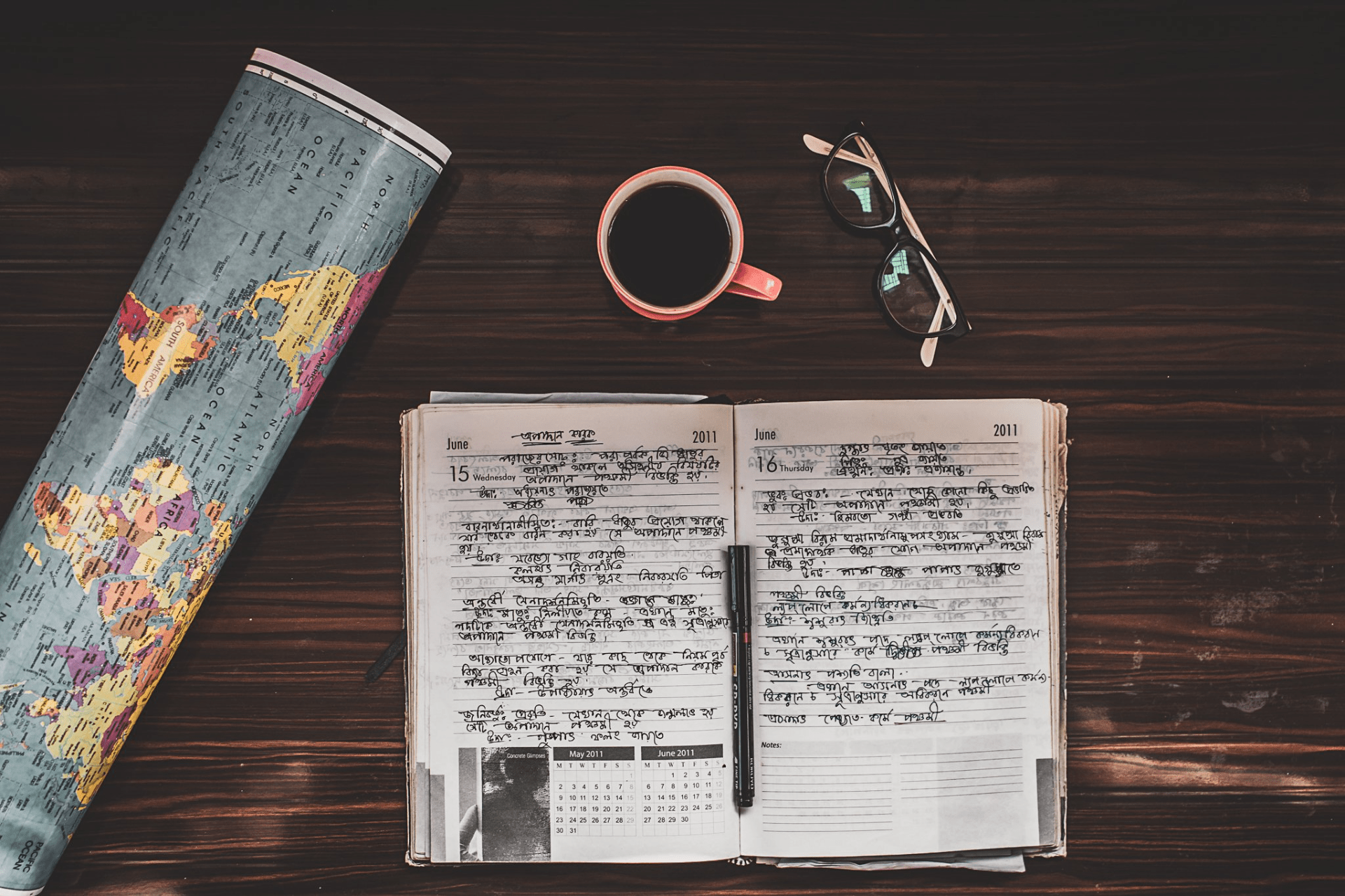 credit: Rahul Pandit. photograph capturing travel, notebook, glasses, coffee and a map, all laid out on a table