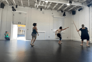 three people move about an empty studio